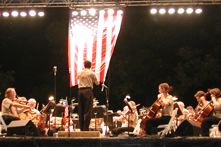 outdoor nighttime concert on stage under American flag