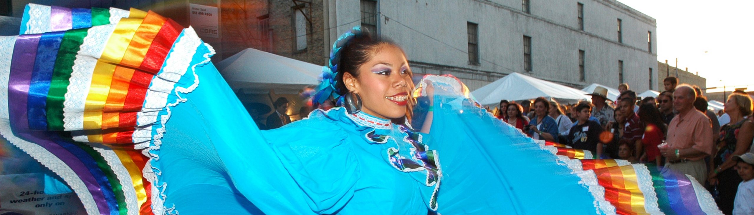 woman performing dance in colorful dress in front of outdoor crowd