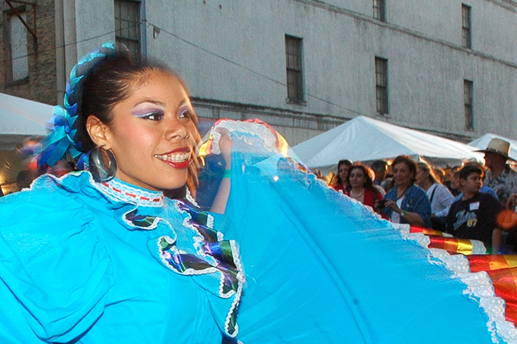woman performing dance in colorful dress in front of outdoor crowd